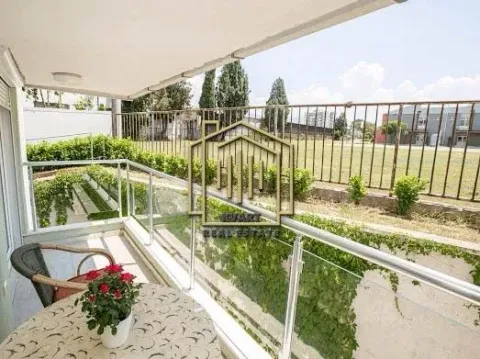 Covered balcony with a table, chairs, and a view of greenery. - image 9
