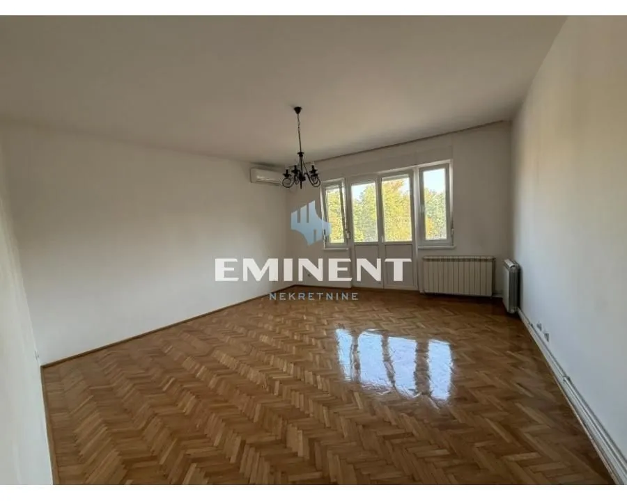 Empty room with hardwood flooring and balcony doors.