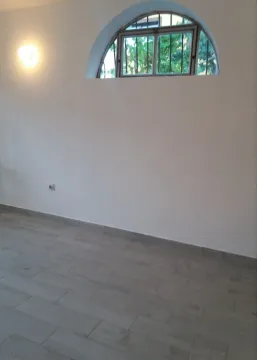 Empty room with white walls, grey tiled floor, and an arched window. - image 5