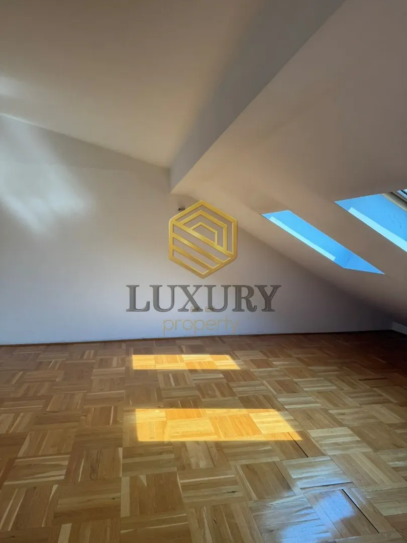 Empty attic room with parquet flooring and skylights.