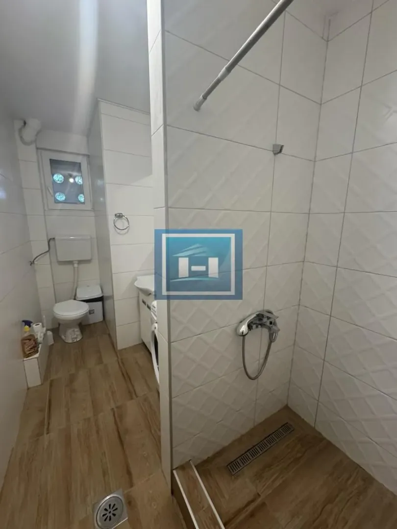 Manje kupatilo sa tuš kabinom i belim keramičkim pločicama.