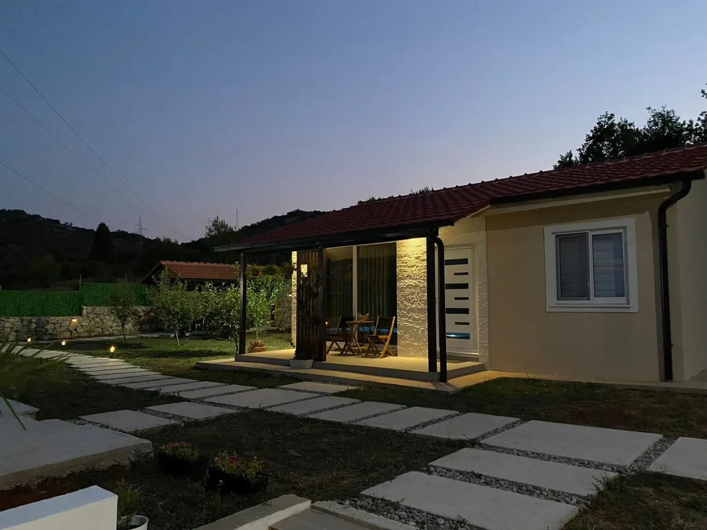 View of the illuminated exterior of the house and yard at dusk.