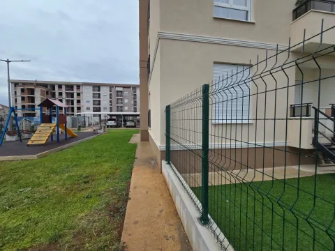Pogled na dvorište i okolne zgrade sa zelenom površinom i igralištem. - image 14