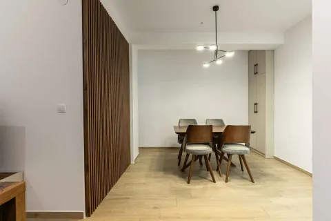 Trpezarija sa drvenim stolom, stolicama i dekorativnim drvenim panelom na zidu. - image 7