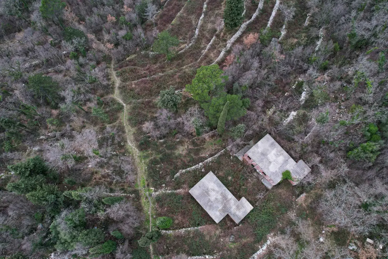 Pogled iz vazduha na zemljište sa započetim objektima okruženim zelenilom.