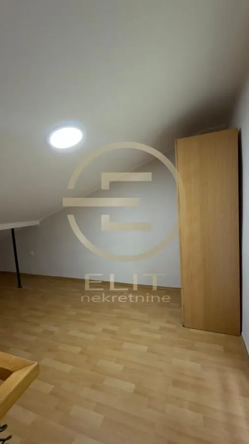 Potkrovlje sa drvenim podom i ugradnim ormarom.