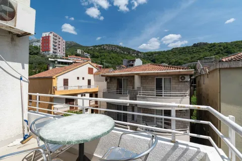 Terrace with a table and chairs and a view of surrounding buildings and hills. - image 9