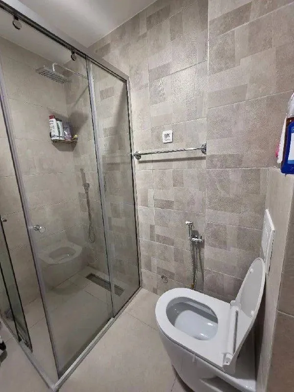 Moderne kupatilo sa tuš kabinom i WC šoljom.