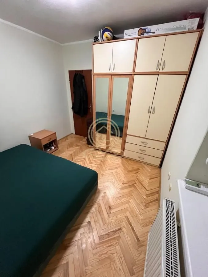 Nameštena spavaća soba sa bračnim krevetom, velikim garderoberom i parketom na podu.