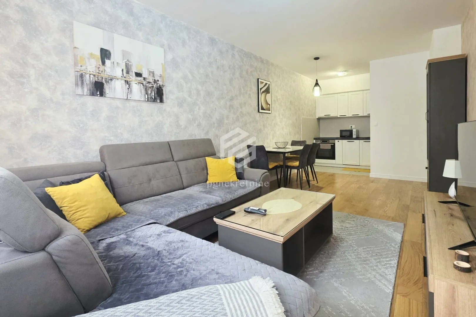 Living room with a sofa, coffee table, and dining area in the background.