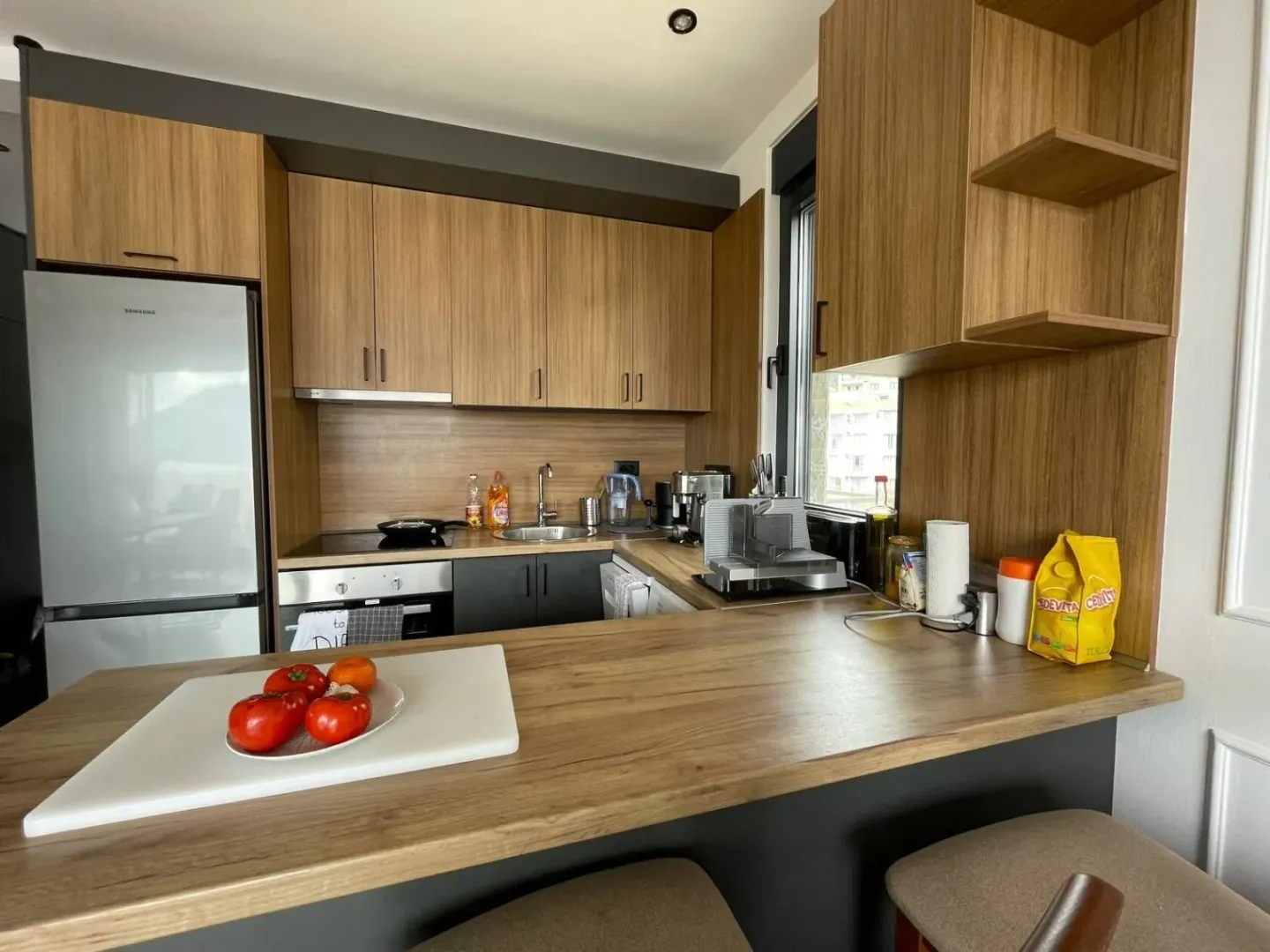 Modern kitchen with wooden cabinetry and a breakfast bar with chairs.