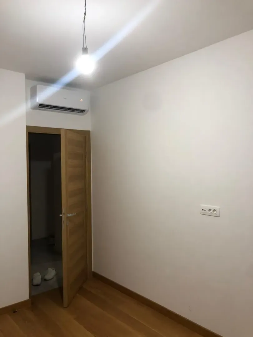 An empty room with a wooden floor and air conditioning.