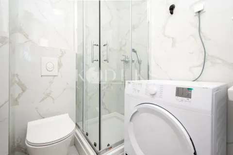 Bathroom equipped with a shower cabin, toilet, and washing machine. - image 6
