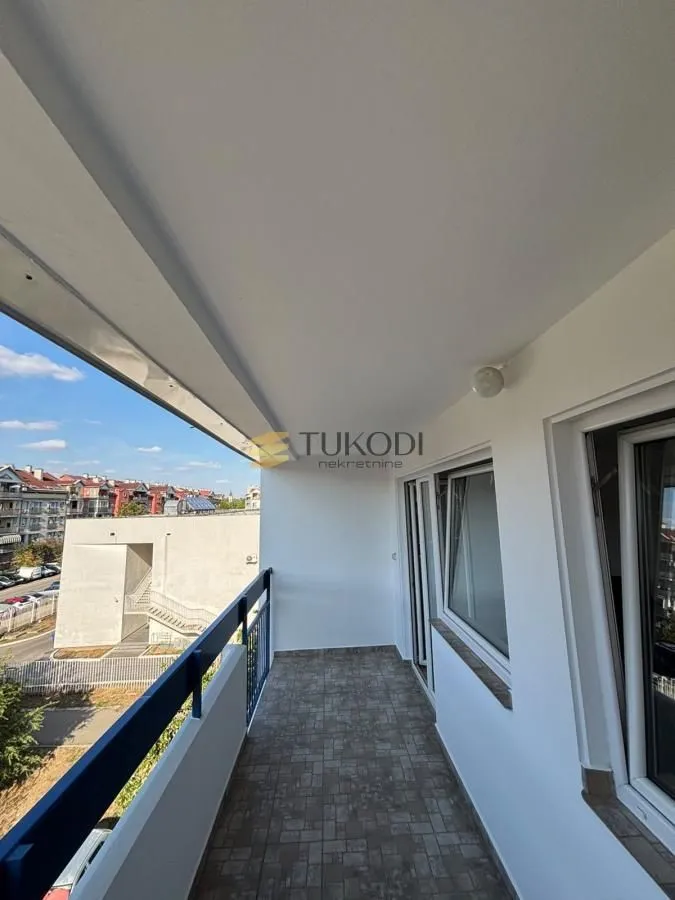 Natkriveni balkon sa pogledom na okolne zgrade i ulicu.