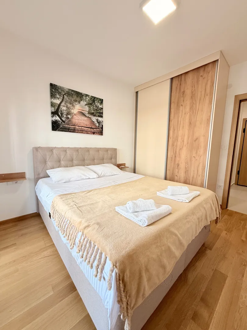 Tidy bedroom with a double bed, wardrobe, and a wall painting.