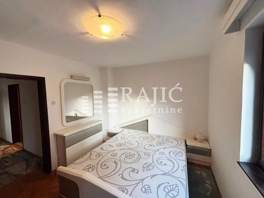Furnished bedroom with a double bed and a mirror.