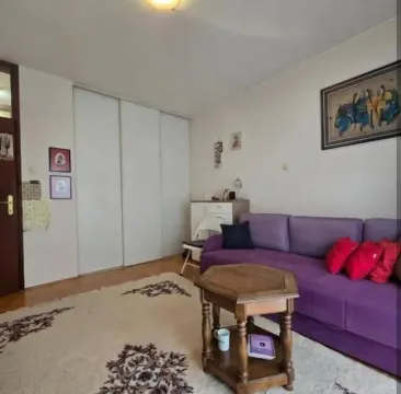 Dnevna soba sa ljubičastom garniturom i drvenim stočićem. - image 2