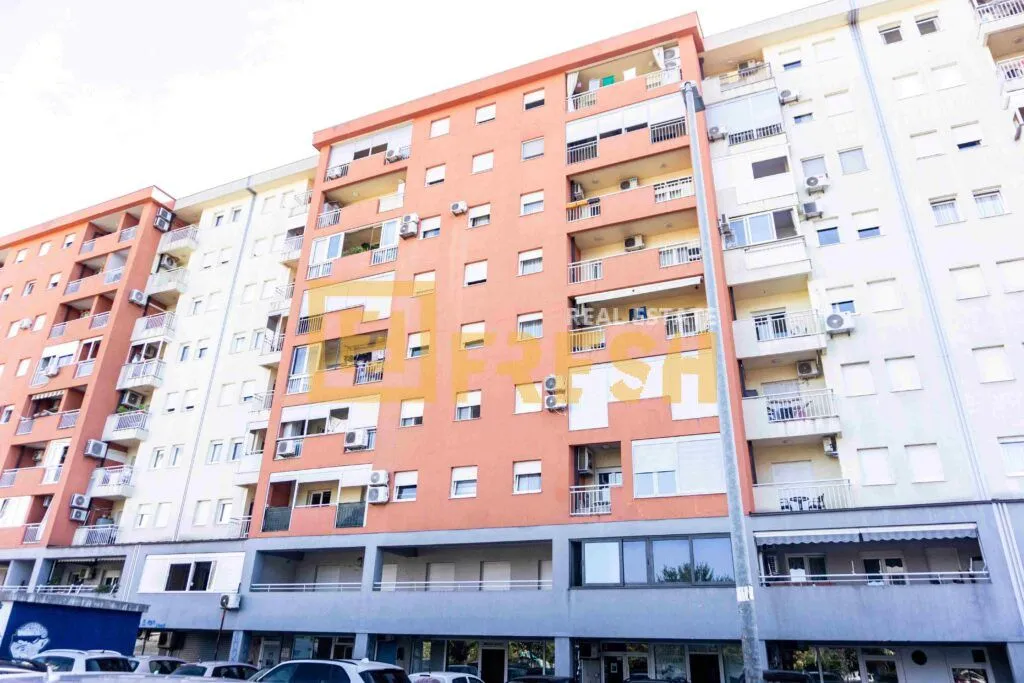 Pogled na spoljašnjost stambene zgrade sa terasam i poslovnim prostorom u prizemlju.
