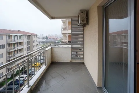 Natkriveni balkon sa metalnom ogradom i pogledom na okolne zgrade i parking. - image 9
