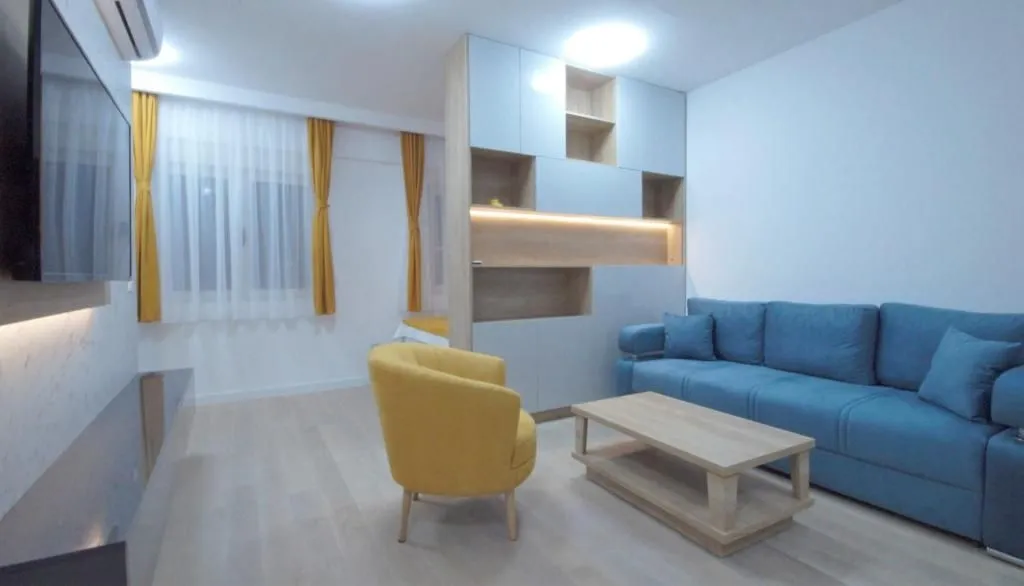 Living room with a blue sofa, yellow armchair, and wall-mounted TV.