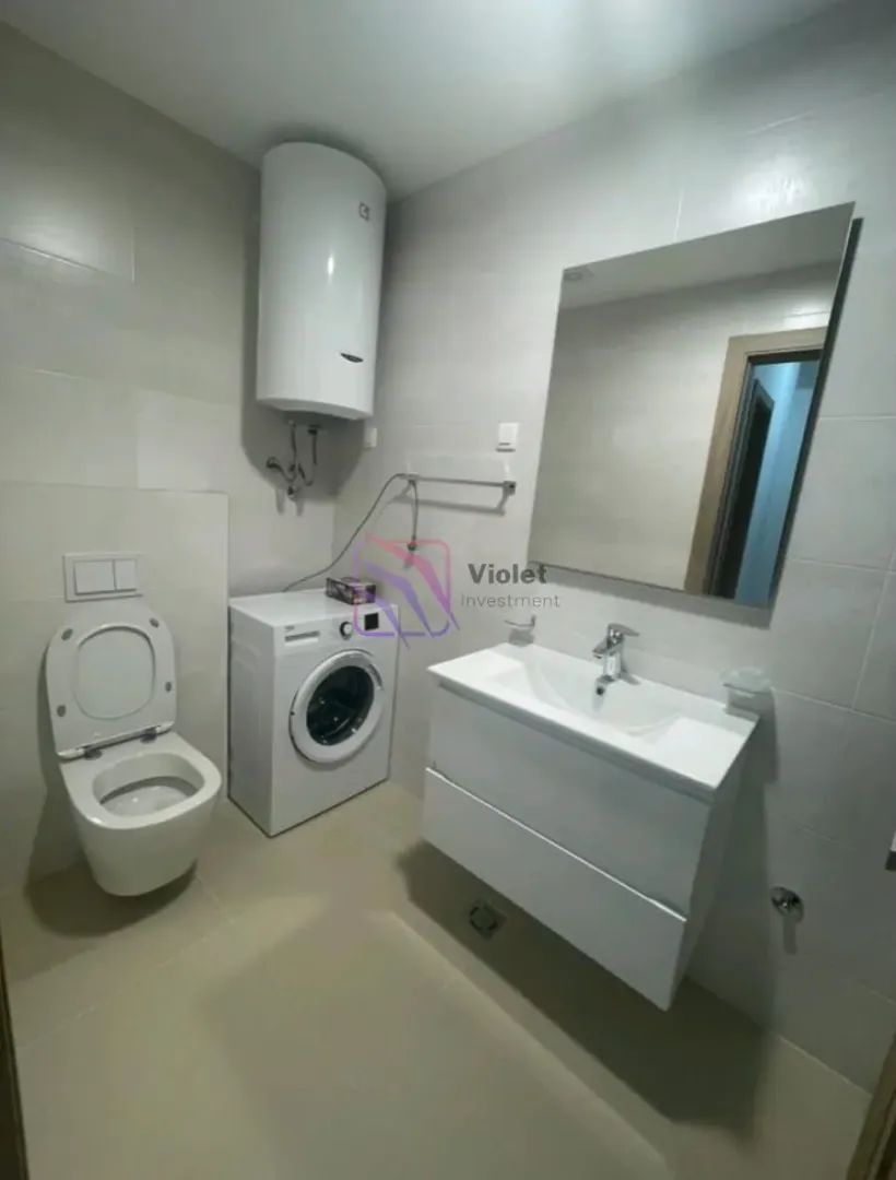 Savremeno opremljeno kupatilo sa sanitarijama, umivaonikom i veš mašinom.