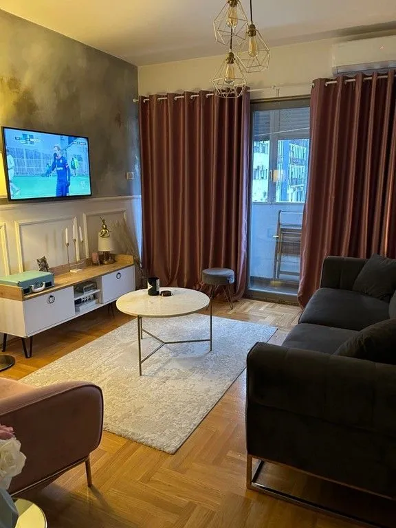 Udobna dnevna soba sa garniturom, televizorom i izlazom na terasu.