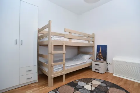 Spavaća soba sa drvenim krevetom na sprat i bijelim ormarom. - image 7