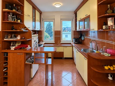 Manja kuhinja sa drvenim elementima, radnom površinom i pogledom kroz prozor. - image 4