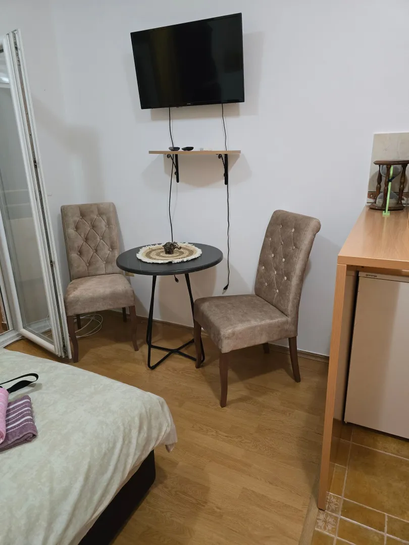 Small living room with a table, two chairs, and a wall-mounted TV.