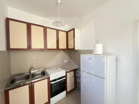 Small kitchen with wooden cabinets, sink, stove, and refrigerator. - image 5