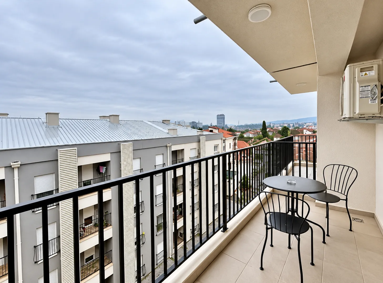 Furnished balcony with a table and chairs and a city view.