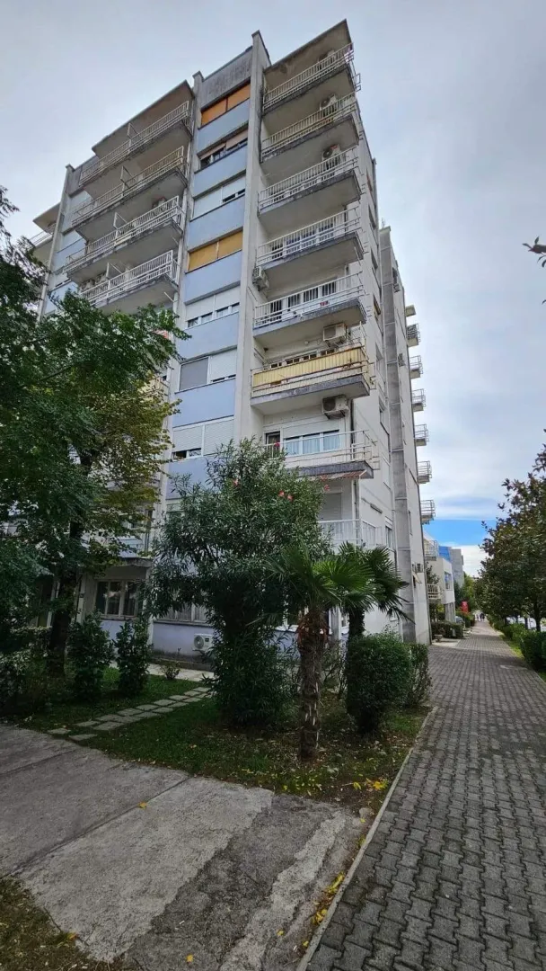Spoljašnji izgled stambene zgrade sa terasama i trotoarom.