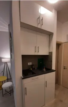 Small kitchen with white cabinets and a built-in sink. - image 7