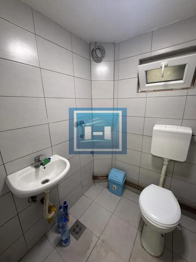 Small bathroom tiled in grey with a washbasin and toilet.