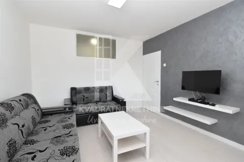 Living room with a sofa, coffee table, and wall-mounted TV. - image 2
