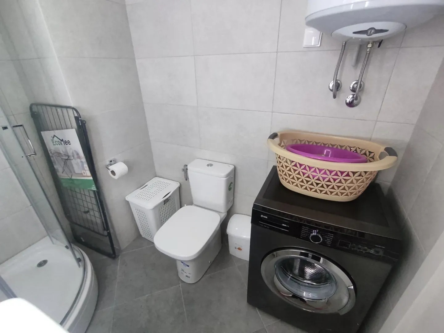Bright bathroom with a shower cabin, toilet, and a washing machine.