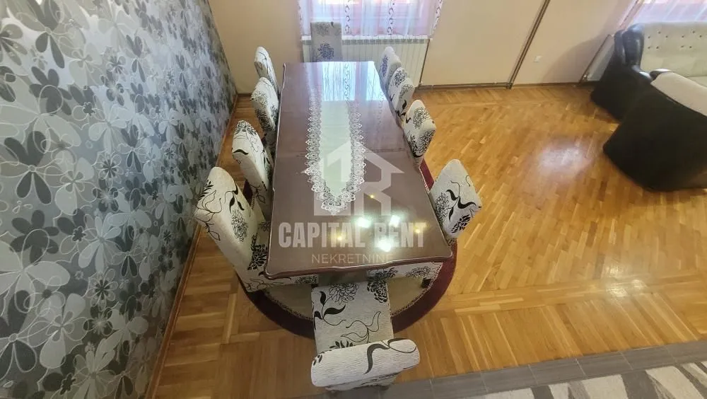 Prostrana trpezarija sa velikim stolom i stolicama u sklopu dnevnog boravka.