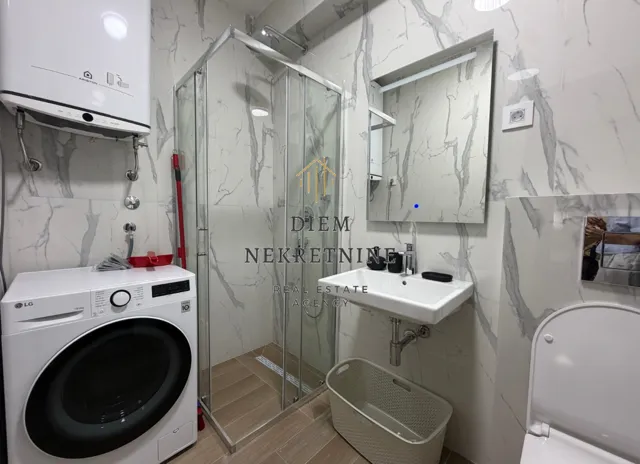 Modernly equipped bathroom with a shower cabin, washbasin, and washing machine.