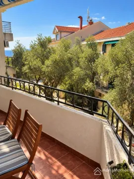 Balcony with wooden chairs and a view of greenery and surrounding buildings. - image 7