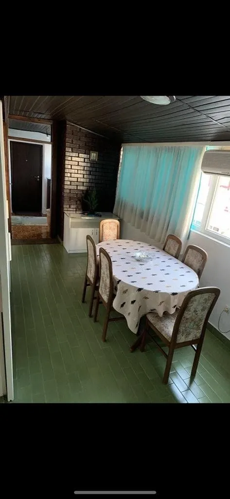 Dining area with a table and chairs, green flooring, and a wooden ceiling.