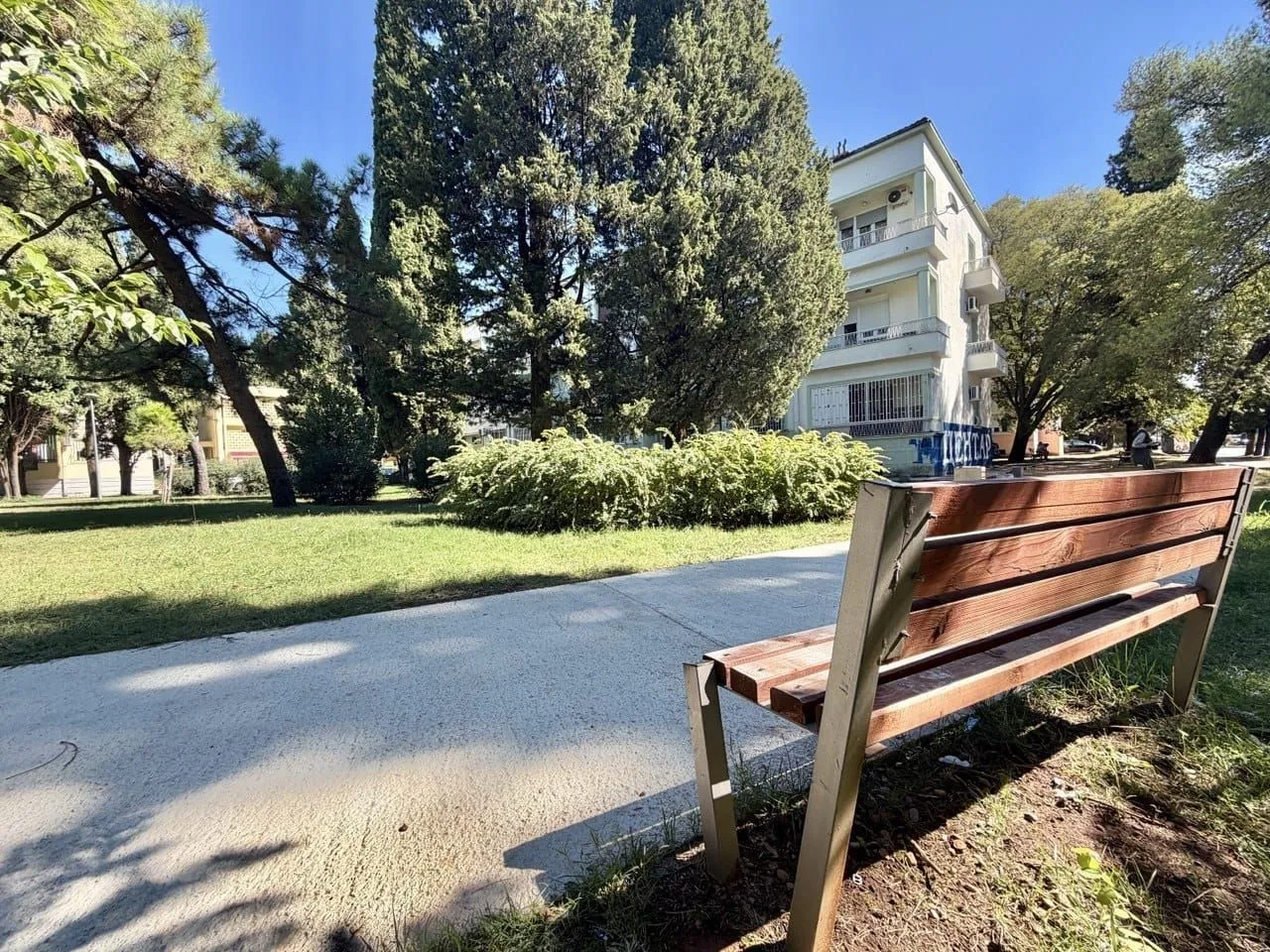 View of the landscaped courtyard with a bench and trees in front of the residential building.