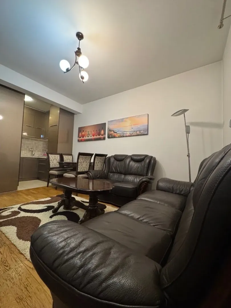 Living room with leather furniture sets and a dining area in the background.
