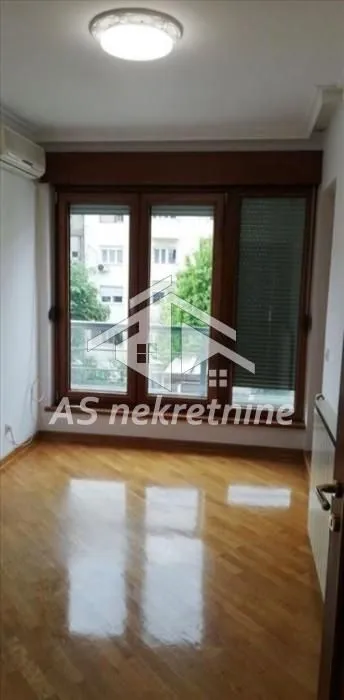 Empty room with wooden flooring, a large window, and an air conditioning unit.