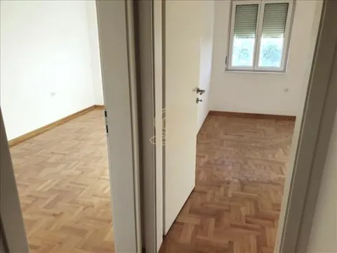 Prazna soba sa parketom i prozorom gledana kroz otvorena vrata. - image 2