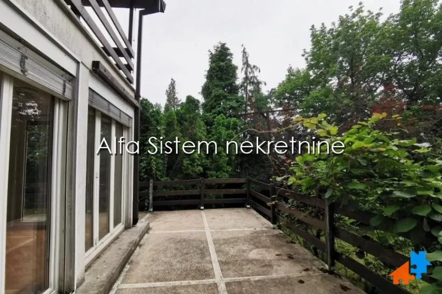 Spacious terrace with a wooden railing and a view of greenery.