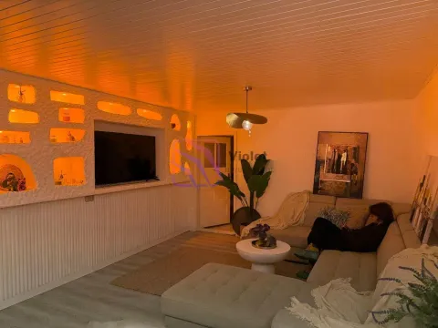 Living room with a sectional sofa, TV, and decorative lighting. - image 11