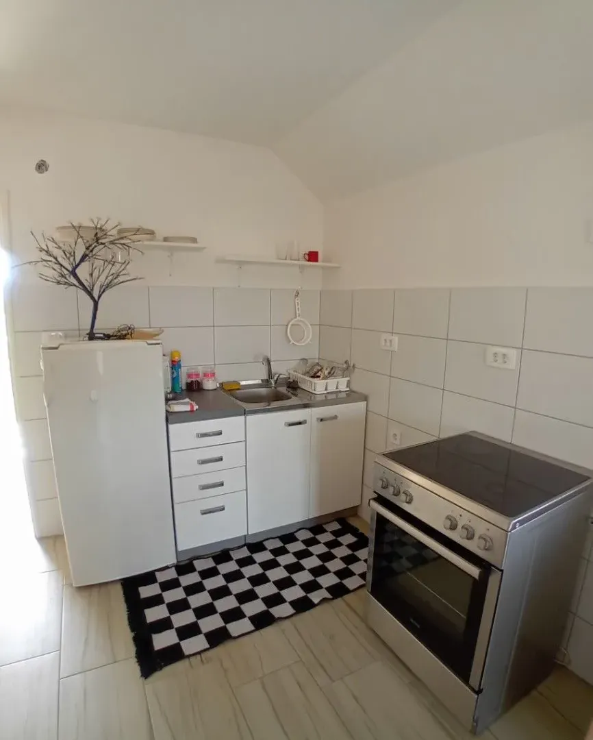 Manja bijela kuhinja sa frižiderom i šporetom.