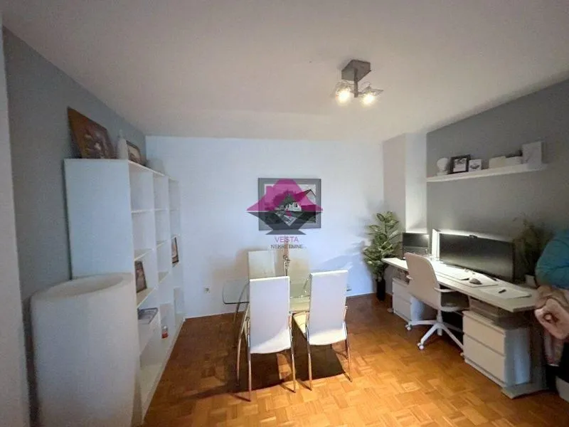 Dnevna soba sa trpezarijskim stolom i radnim stolom sa računarom.