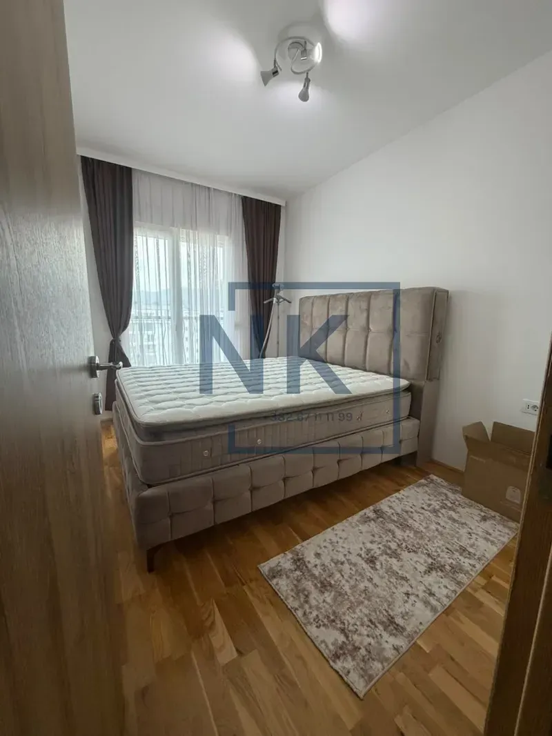 Bedroom with a double bed, wooden flooring, and a window with curtains.