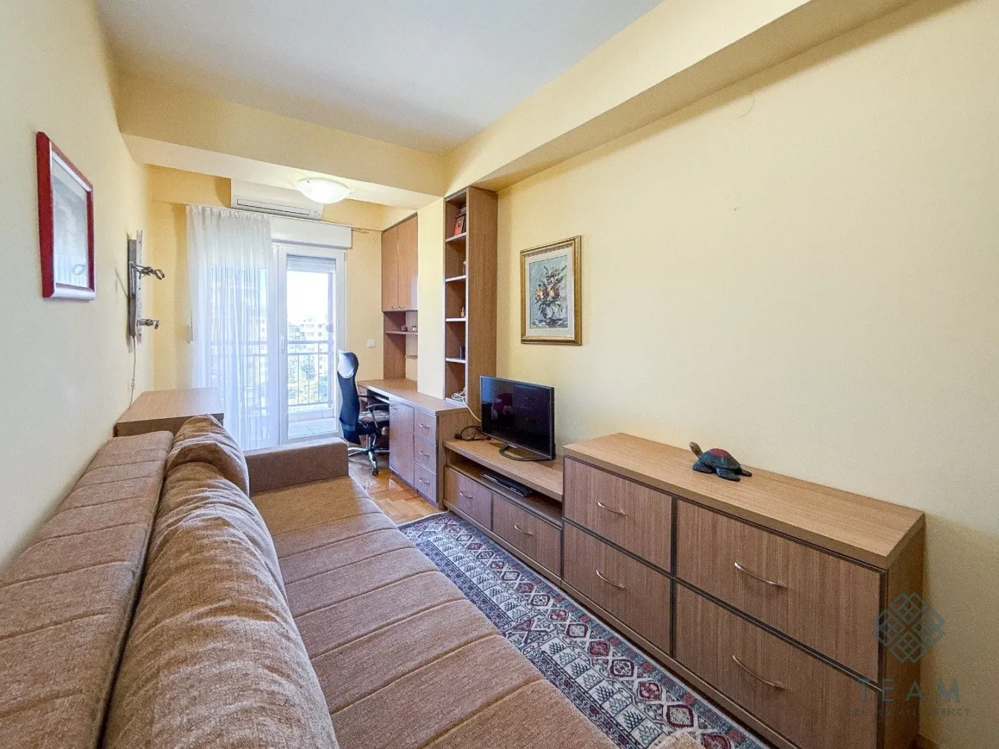 Living room with a sofa, TV unit, and desk.